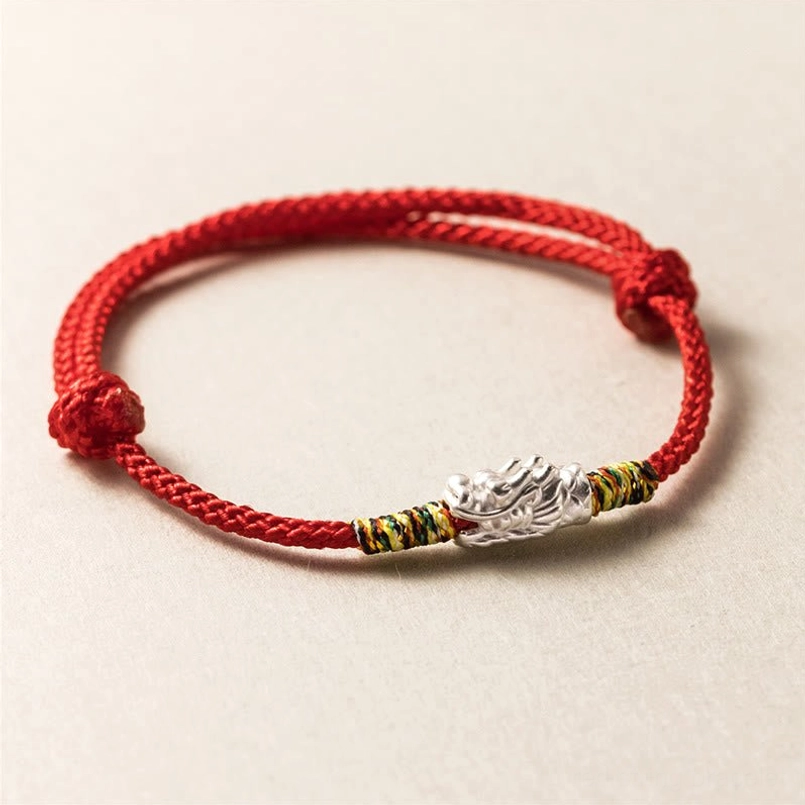 Silver dragon head red string bracelet with woven cord and adjustable knots flat lay