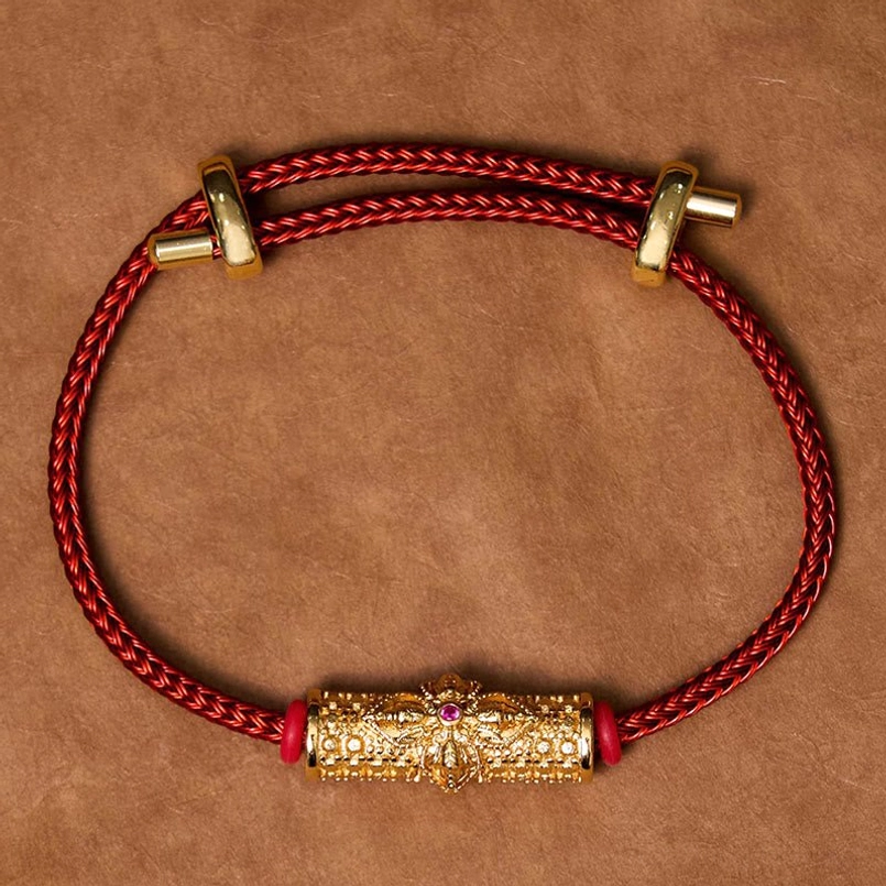 Red string copper luck bracelet display showing silver metal and colorful flower design