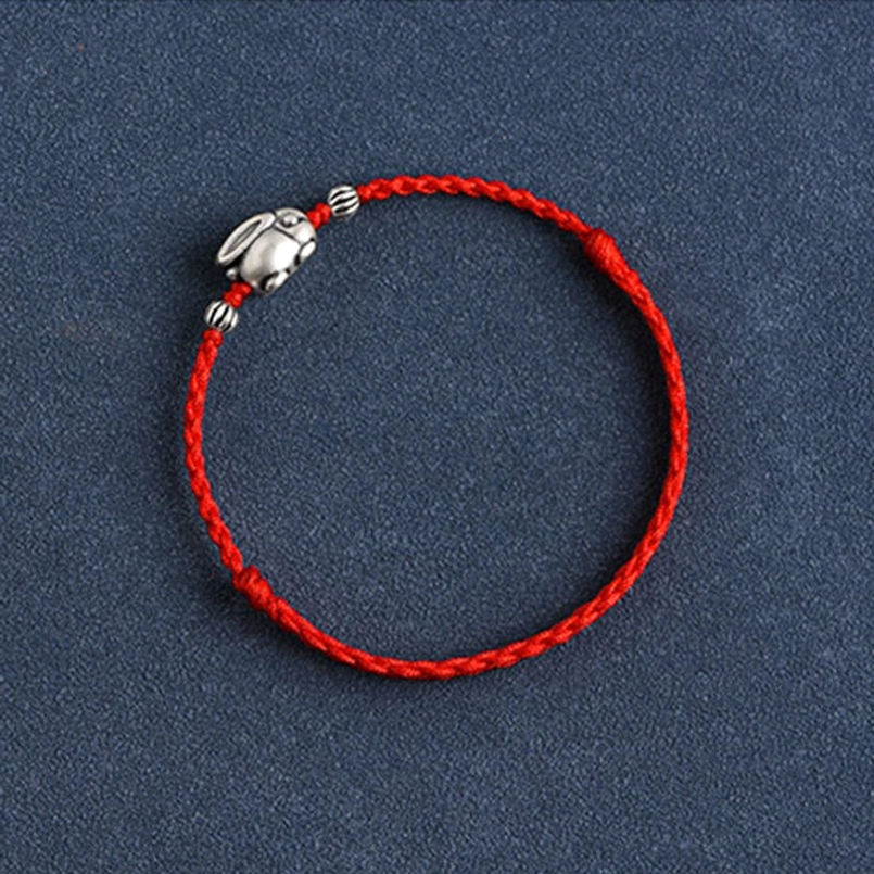 Close-up macro of textured silver accent beads on red braided cord