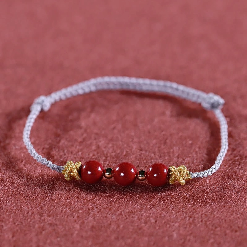 Silver string cinnabar bracelet front flat view with decorative knots