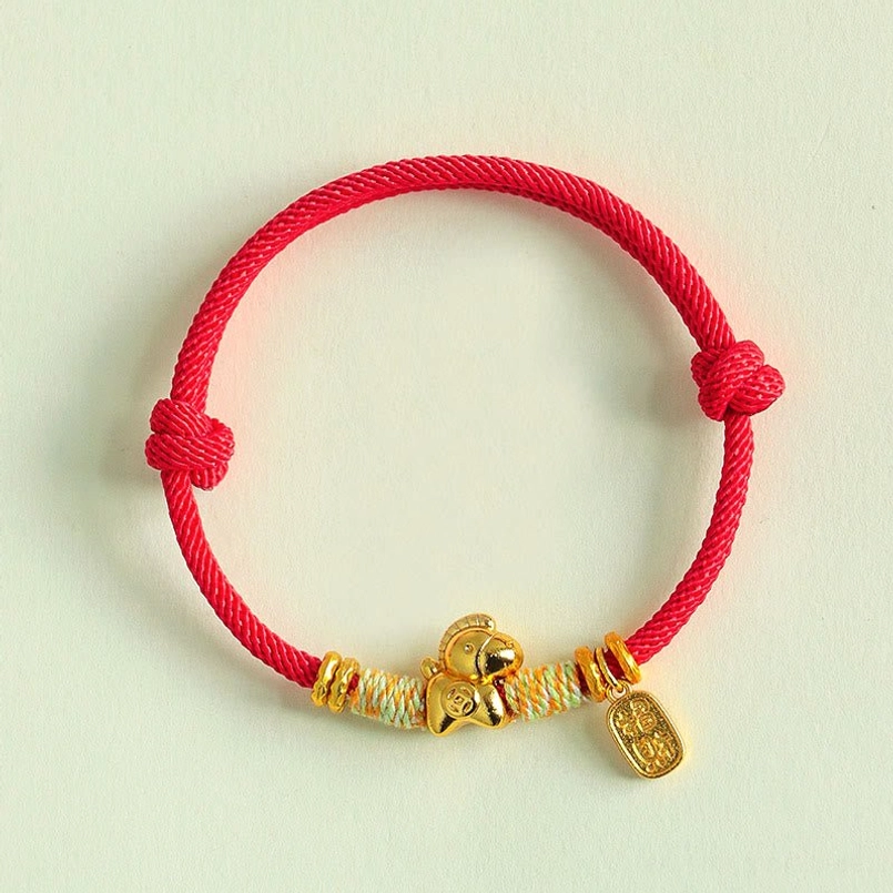 Simple adjustable braided red string bracelet dual sliding knots light green background