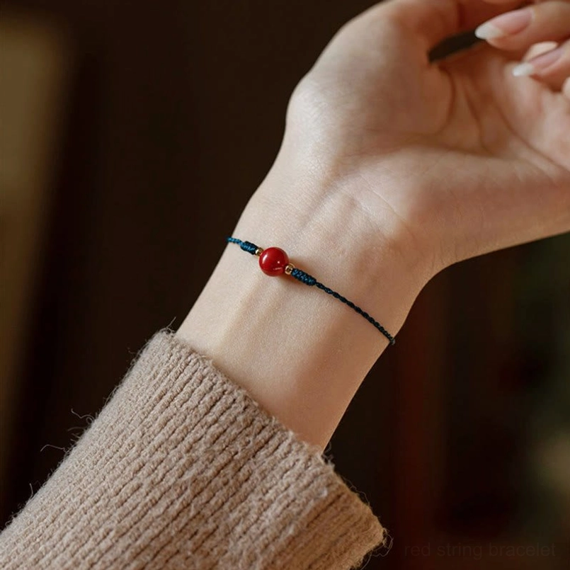 Partial close up of cinnabar bracelet fitting slim wrist with beige knit sleeve