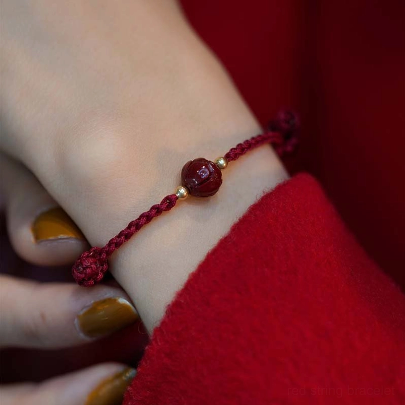 Simple smooth cinnabar bead bracelet with wine-red rope and gold accents on wrist