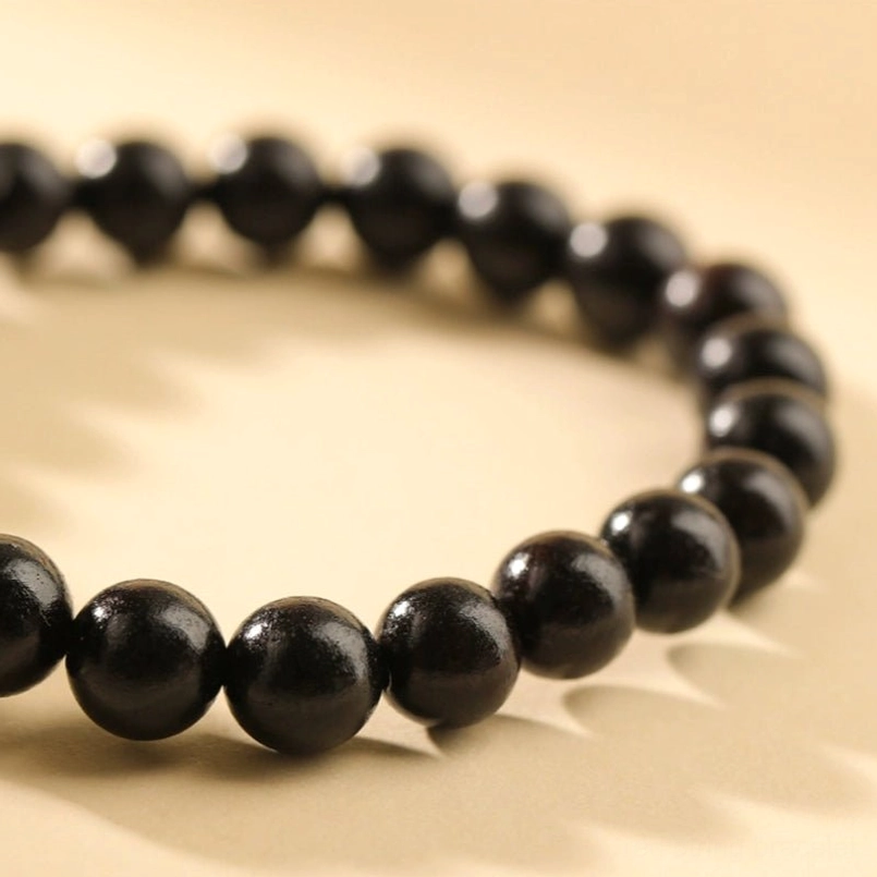 Smooth matte black ebony wood beads red string bracelet partial view