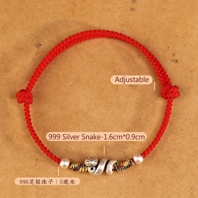 Close-up flat lay of red string anklet with product specifications labeled, showing 999 sterling silver snake charm and 5mm silver round beads