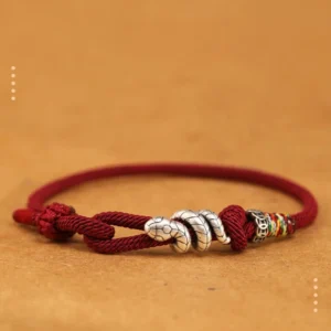 Year of the Snake red string bracelet with silver snake charm and adjustable knot, front view flat lay