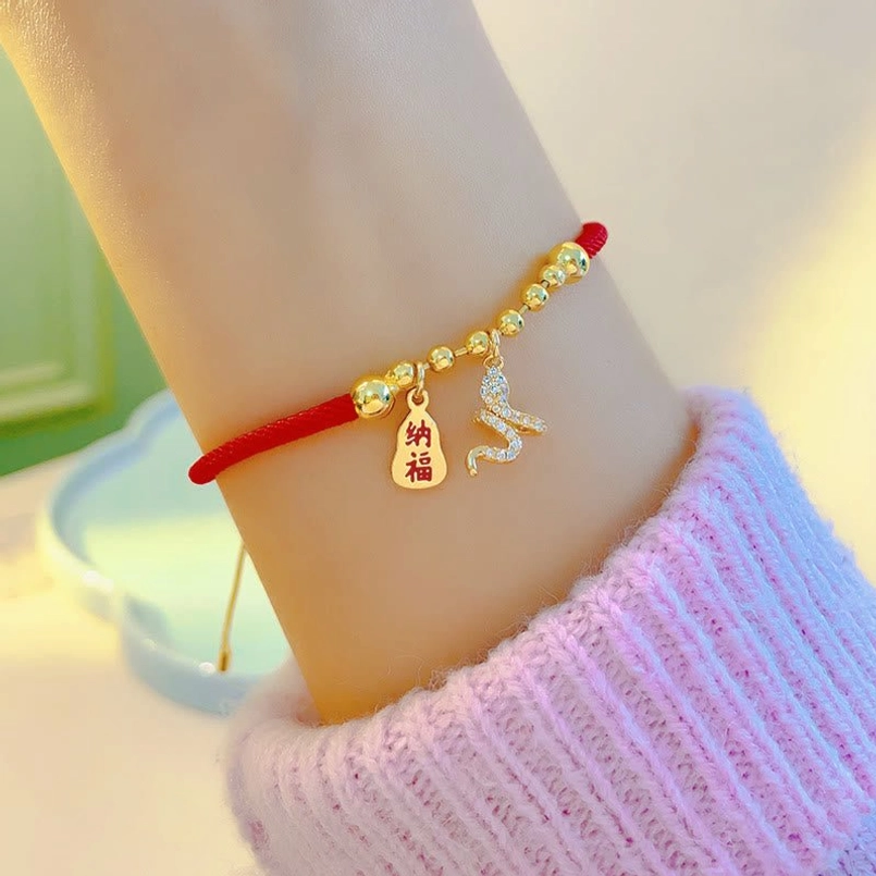Snake zodiac red string bracelet side wrist view with pink knit sleeve