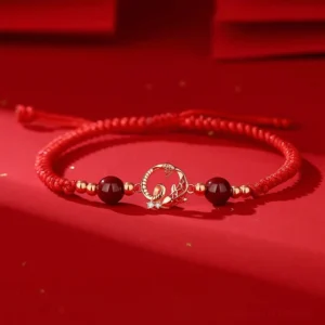 Year of Snake red string protection bracelet with cinnabar beads and gold snake koi charm, flat lay top view