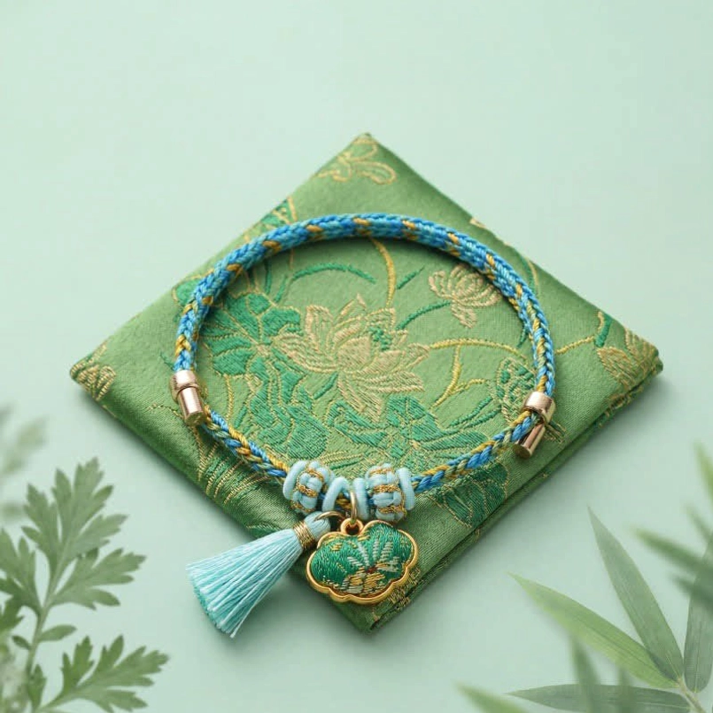 Lucky charm red string bracelet with five-color woven cord apple-shaped pendant and matching tassel on green brocade mat