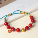 South Red Agate 8mm beaded success bracelet with gold ingot charm on desk with book background