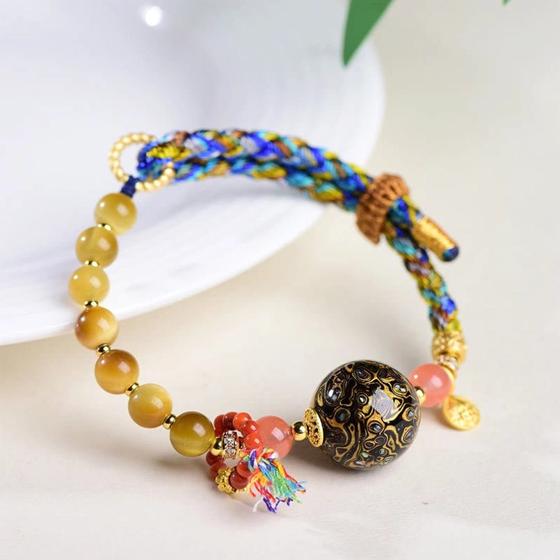 Protection red string bracelet with tiger eye stone and Tibetan lacquer bead on white ceramic plate