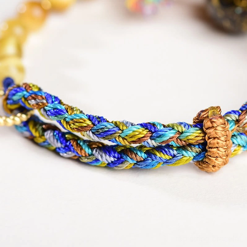 Tibetan lacquer tiger eye red string bracelet placed on spiritual healing crystal background
