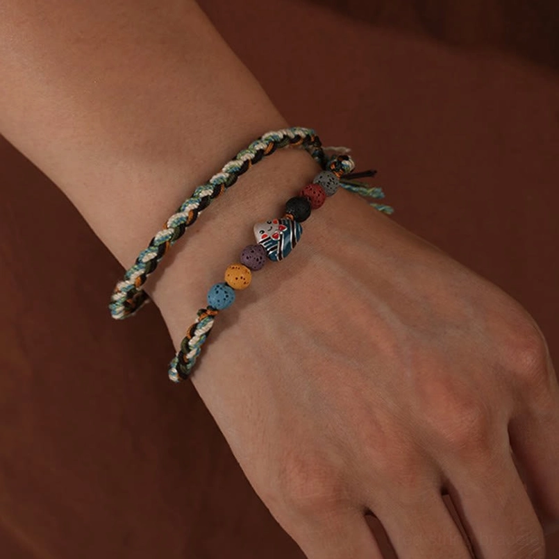 Stackable woven luck red string bracelet worn on human wrist