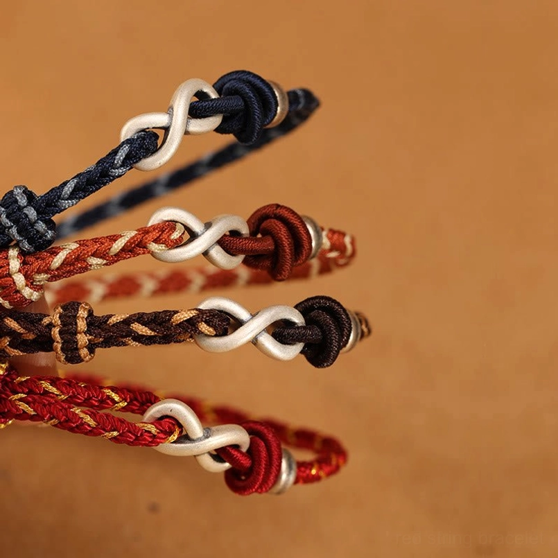 Close-up detail of silver infinity charm and knot clasp on colored rope bracelets