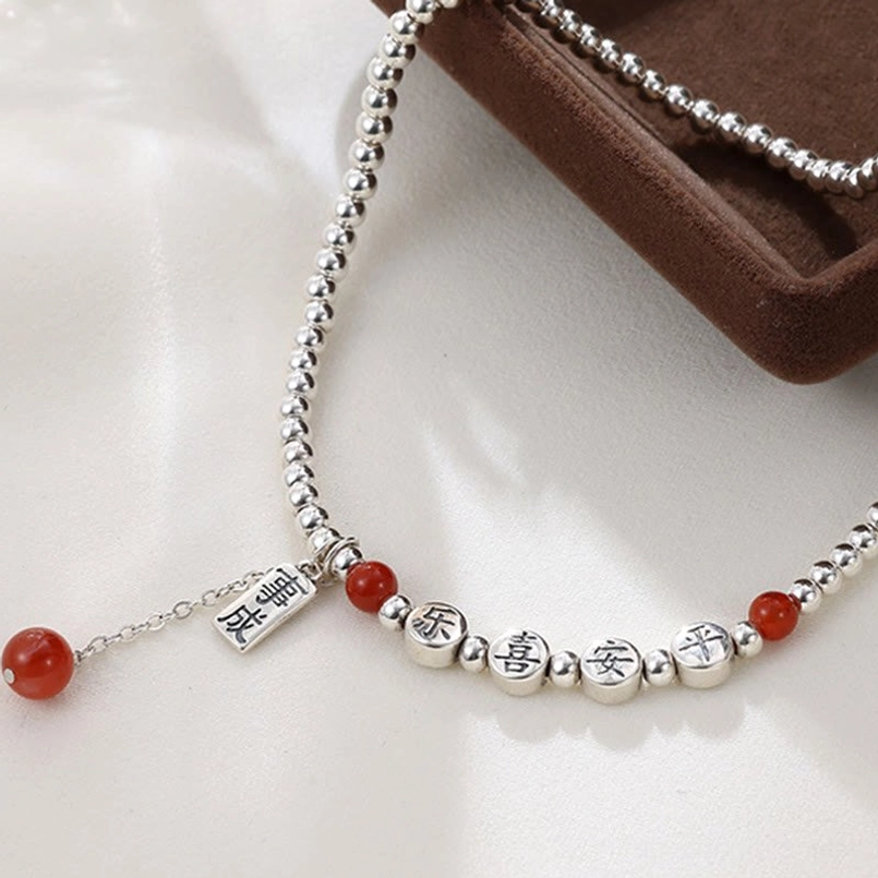 Flat lay view of sterling silver red agate peace and joy blessing anklet with success dangling charm