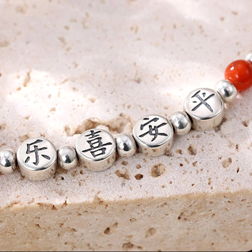 925 sterling silver red agate blessing anklet with multiple protective charms displayed on brown tray