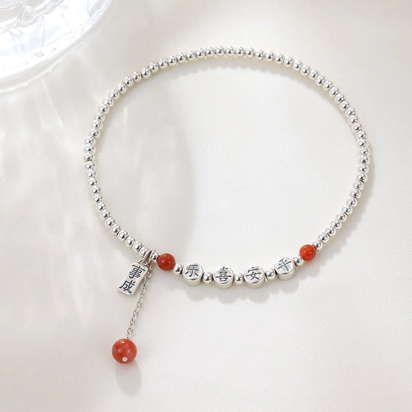 Flat lay top view of sterling silver blessing anklet with red agate beads and engraved Chinese character charms
