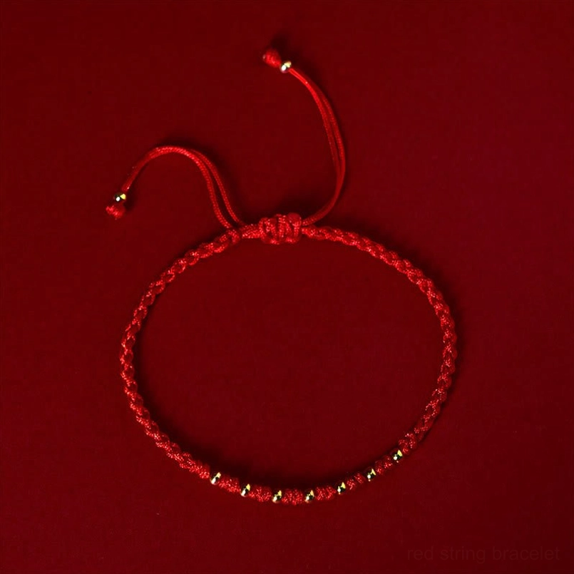 Red braided string bracelet with adjustable knots and gold metal beads closeup
