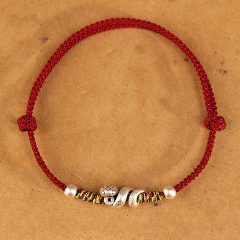 Sterling silver snake anklet with adjustable red string featuring protective charm design and artisanal craftsmanship details
