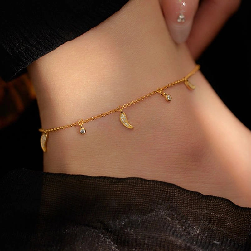 Side ankle wearing view of sterling silver zircon pepper charm anklet with styled manicure