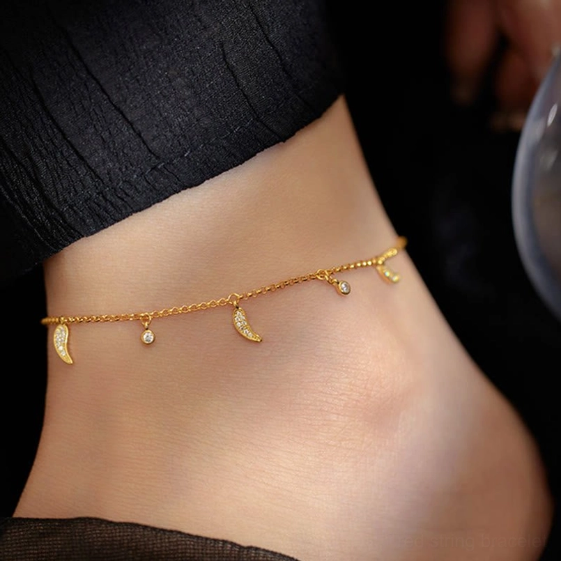 Protection anklet worn on ankle rear view - showing pepper charms and zircon drops with dark fabric backdrop