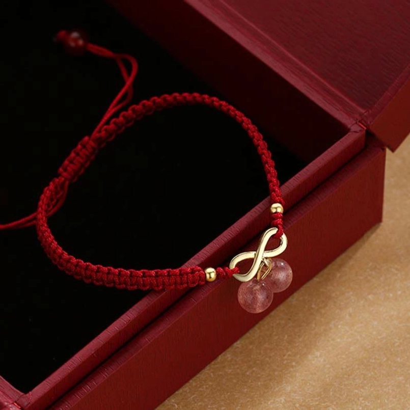 Close-up detail of infinity knot charm and pink strawberry quartz beads on braided red cord