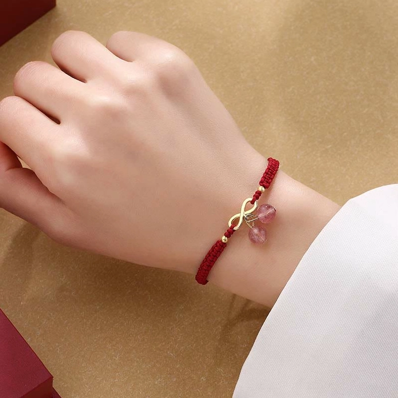 Infinity knot red string bracelet on wrist showing paired strawberry quartz crystal drops