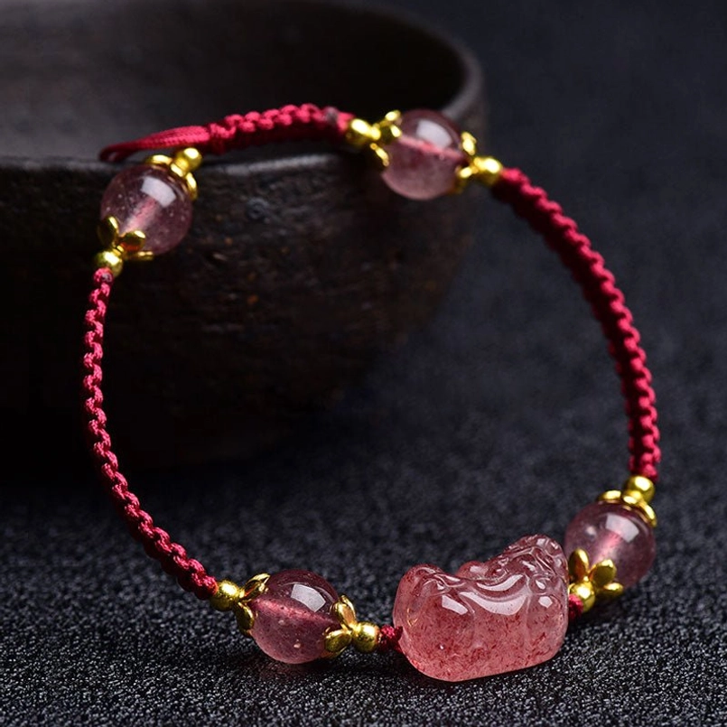 Rose pink strawberry quartz beads arranged with Pixiu charm on dark background