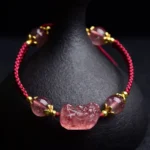 Strawberry Quartz Pixiu Red String Bracelet with gold accents and ceramic vase