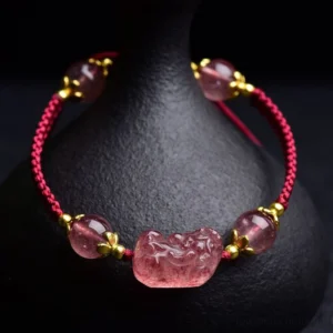 Strawberry Quartz Pixiu Red String Bracelet with gold accents and ceramic vase