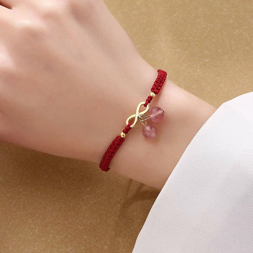Red string bracelet with gold infinity charm and dangling strawberry quartz beads on wrist