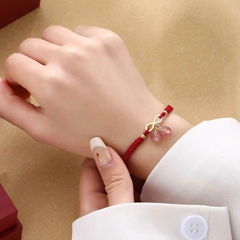 Strawberry quartz red string bracelet worn on left wrist with double cherry pendant detail