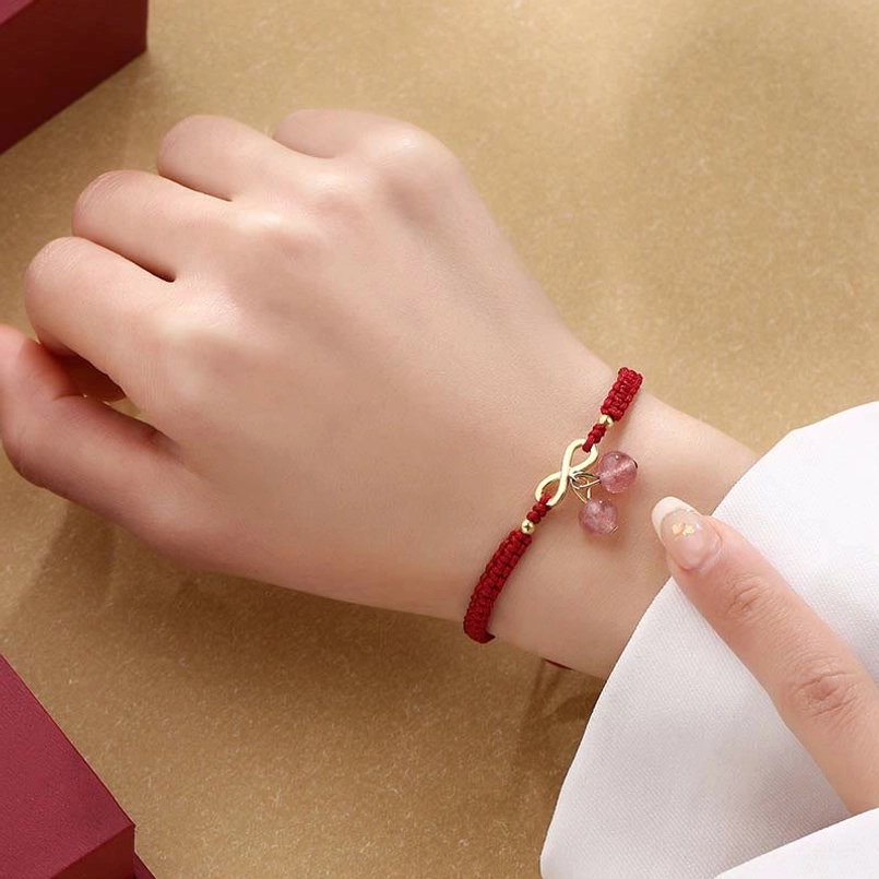 Red string love bracelet on right wrist with clear strawberry quartz pendant design