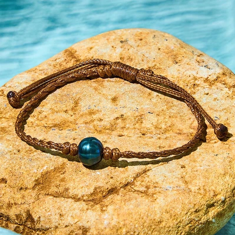 Tahitian black pearl adjustable bracelet flat lay - natural stone background showing sliding knots