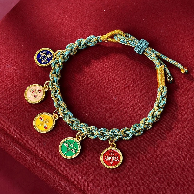 Top view of teal five gods of wealth braided lucky string bracelet on red velvet background