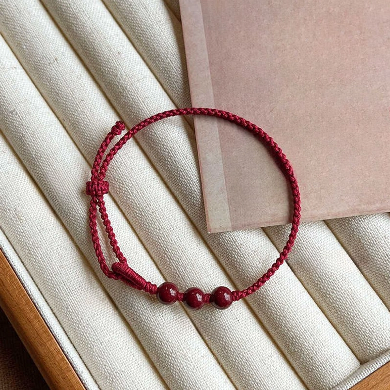 Thin braided red string bracelet with three natural cinnabar beads