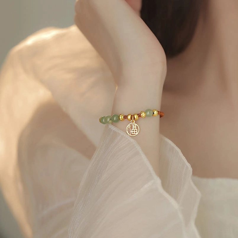 Mini thin jade fu red string bracelet on hand with white linen sleeve