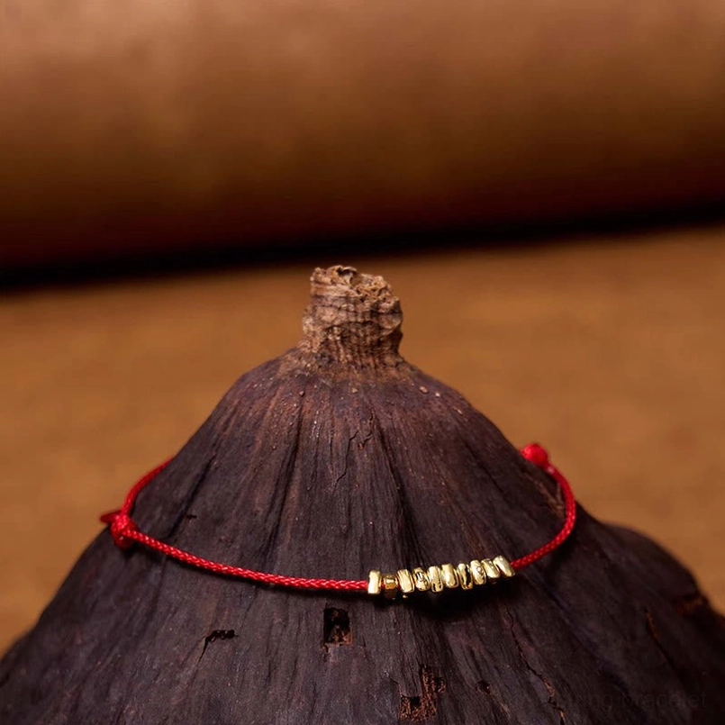 Close-up side view of ultra-thin red braided rope bracelet with silver accent