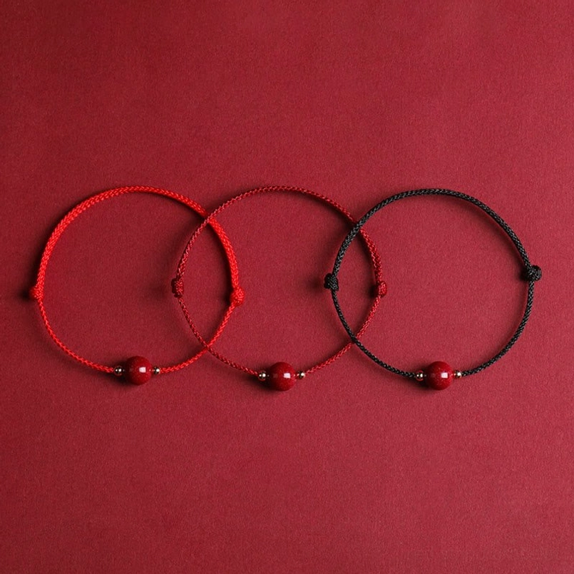 Set of three cinnabar bead bracelets with two red and one black braided cord display