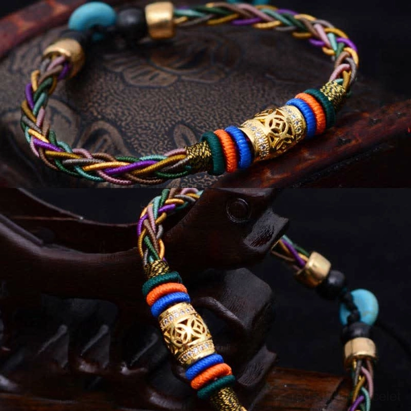 Close-up of tibetan braided red string bracelet with carved metal decoration