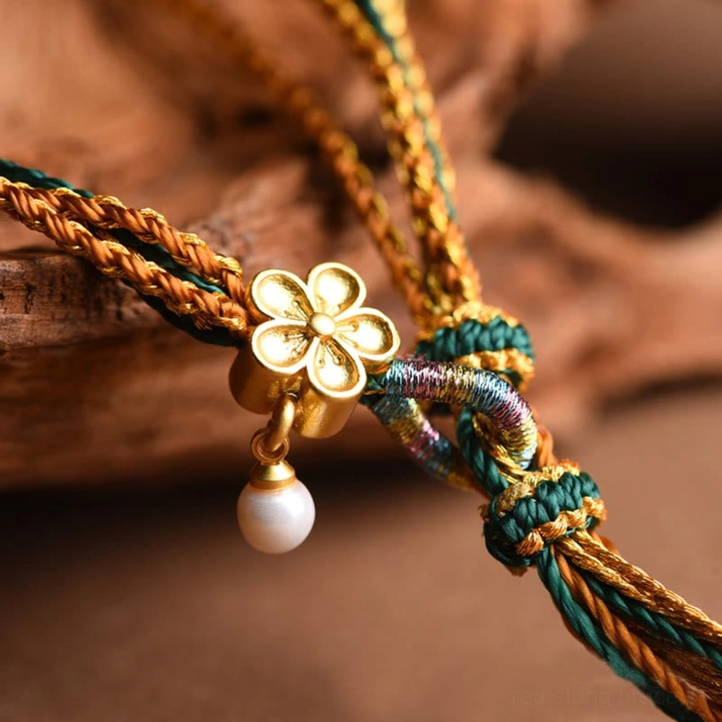 Tibetan braided bracelet macro shot showing knot craftsmanship and gold four-leaf flower charm