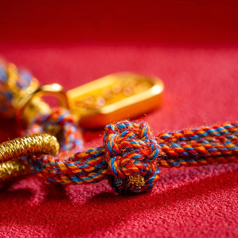 Tibetan Om Mani Padme Hum bracelet knot detail with braided multicolor rope and gold metal parts macro view