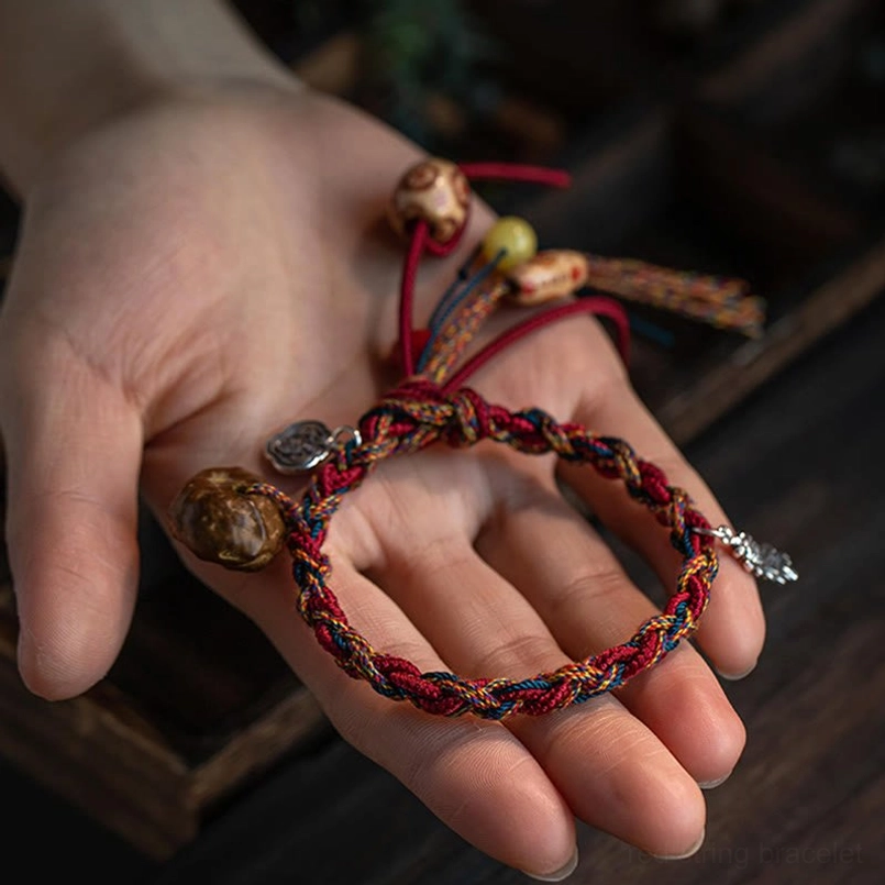 Handmade tribal tibetan bracelet in hand featuring multicolor braided rope and silver leaf charm