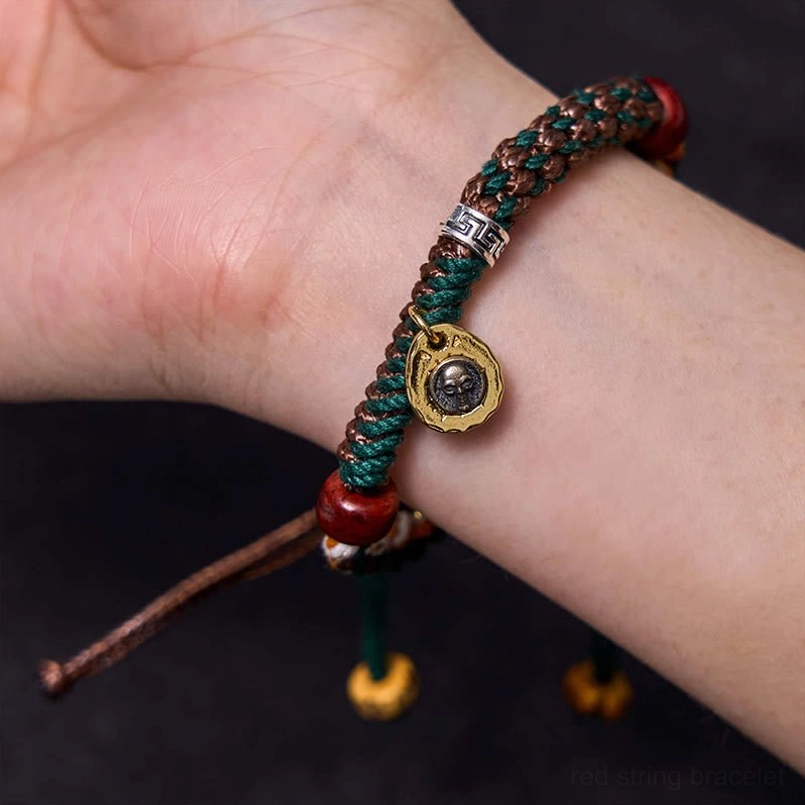 Tibetan red string bracelet worn on bare wrist close up side view