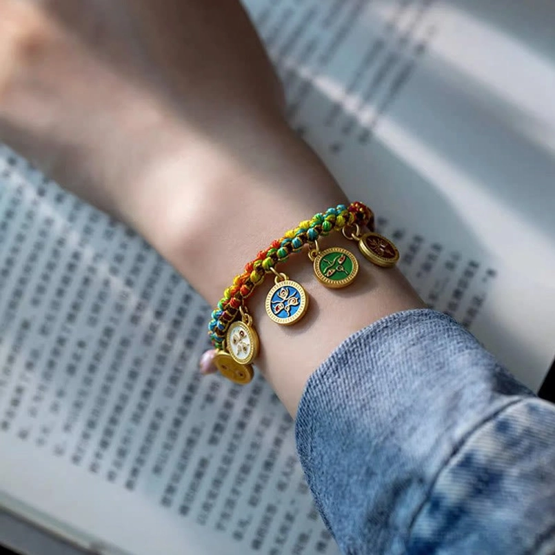 Tibetan Five God prosperity bracelet with colorful cord worn on wrist near book