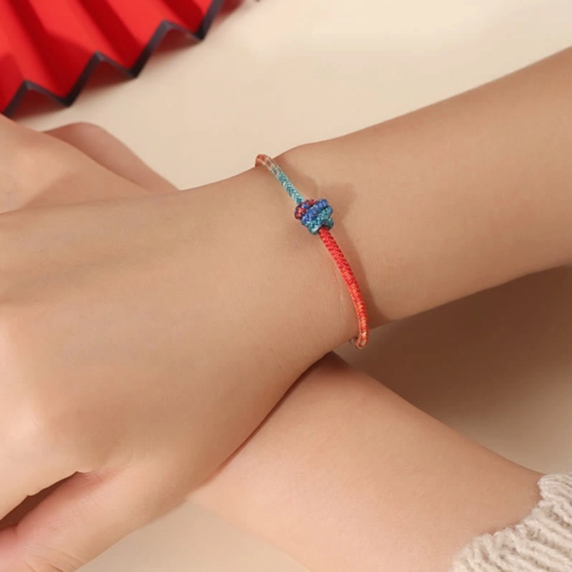 Red string bracelet worn on human wrist showing comfortable fit and gradient color design