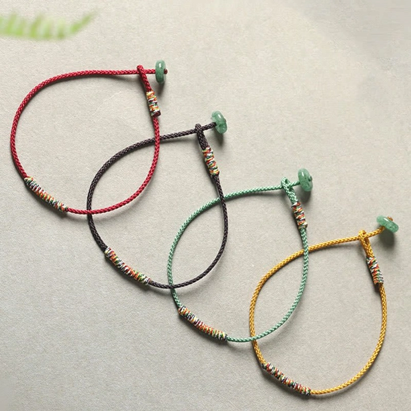 Set of multiple Tibetan lucky bracelets in various colors with green aventurine pendants displayed flat lay