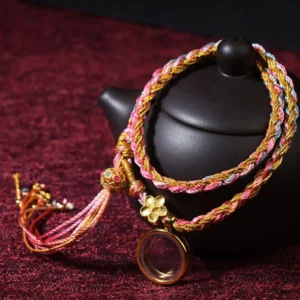 Tibetan lucky braided colorful string bracelet double wrap with copper flower charm and metal pendant on burgundy fabric background