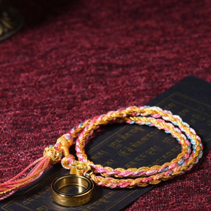 Colorful Tibetan braided lucky string bracelet with metal flower charm and ring pendant displayed with black scripture card