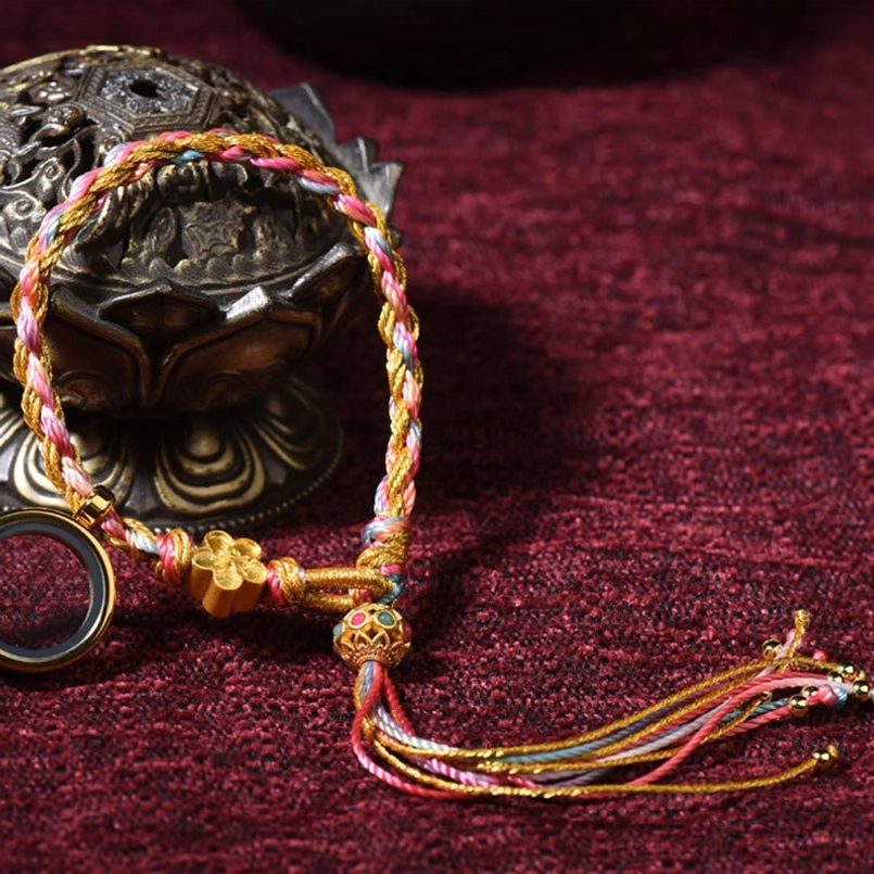 Tibetan handmade braided lucky string bracelet with mixed color braid, metal flower charm and long decorative tassel on burgundy background